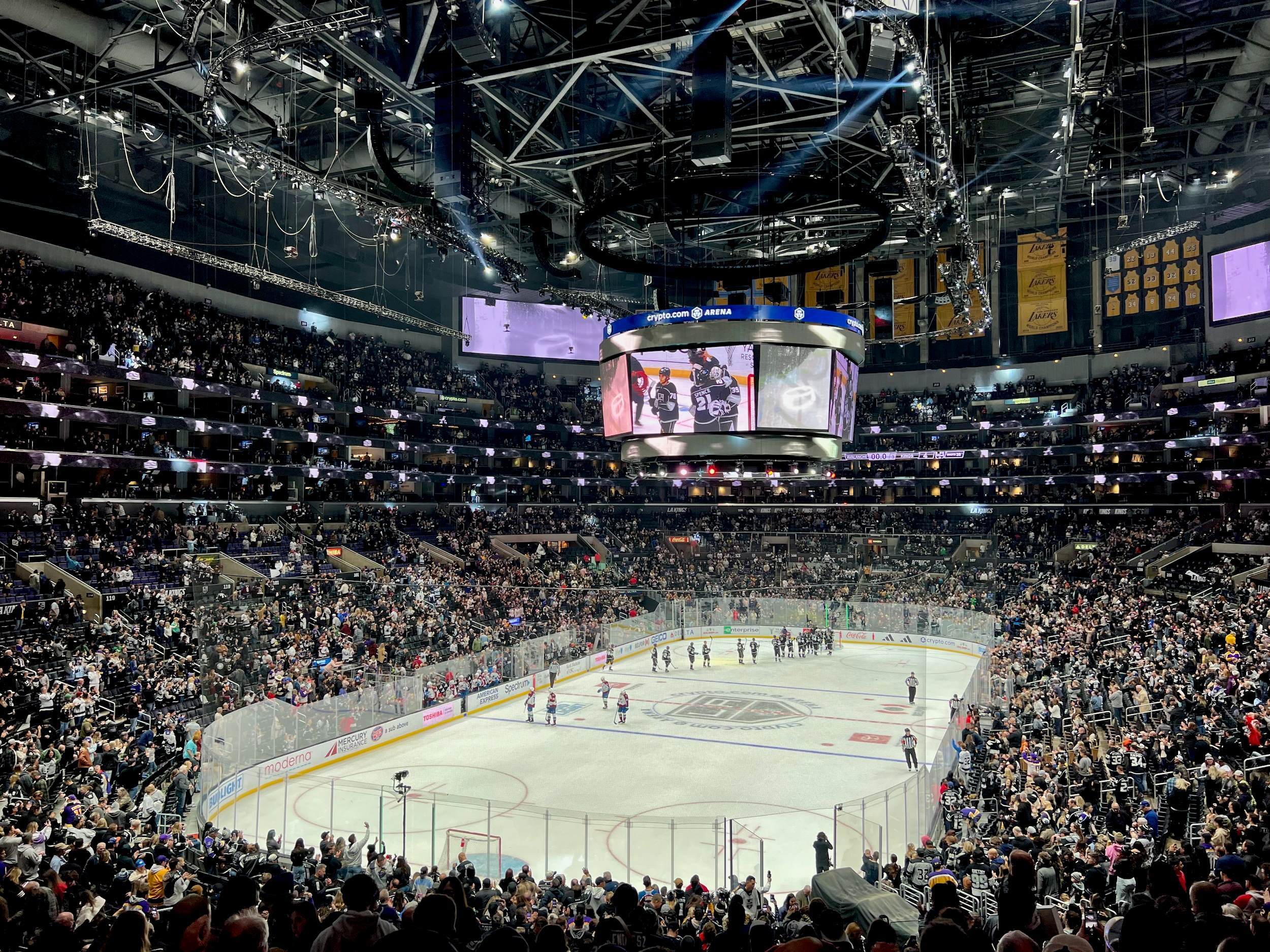 Hockey players on ice surrounded by a full stadium of people