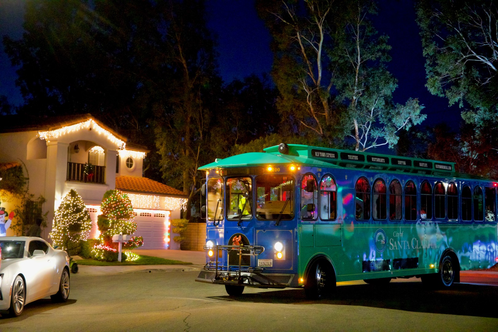 Transit bus driving through neighborhood with holiday lights