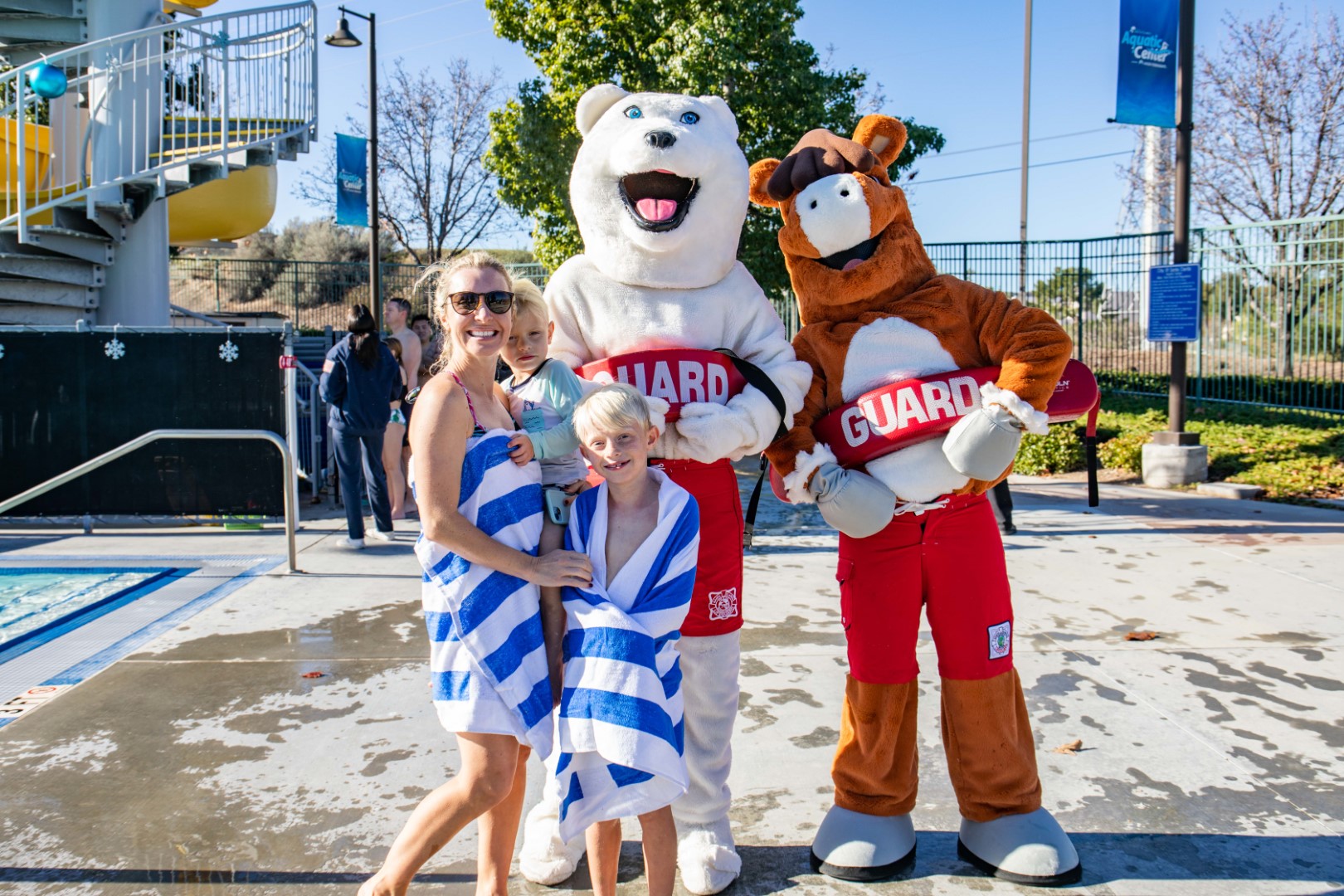 Family smiling with Polar Bear mascot and Sammy Clarita after completing the Polar Plunge