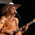 Woman in Western gear playing guitar and singing