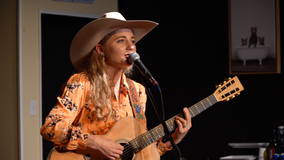 Woman in Western gear playing guitar and singing