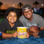Father and son smiling with a bucket or popcorn