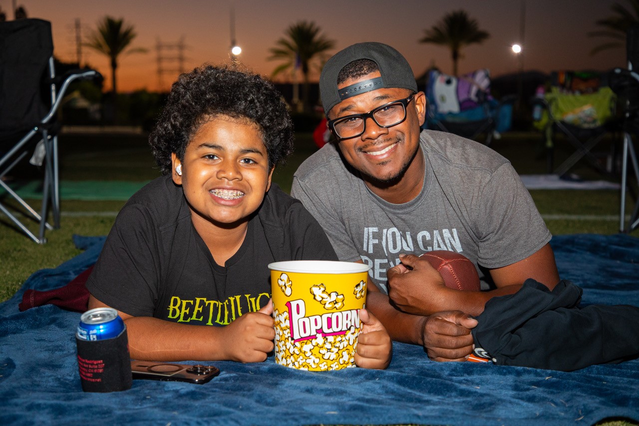 Father and son smiling with a bucket or popcorn