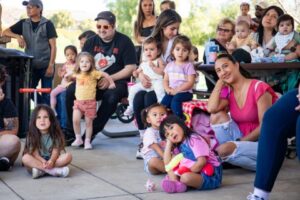 Families sitting outside listening to a book