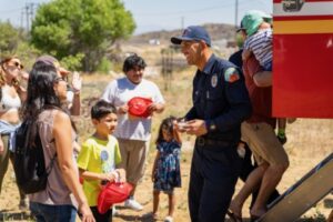 Families listening to a fire fighter and exploring a fire truck