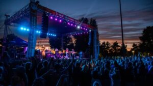 Dusk photo of concert, with blue and pink lights lighting up the cheering crowd