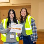 Two Volunteers wearing yellow vests holding a sign for the 2026 Greater Los Angeles Homeless Count.