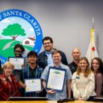Volunteers taking photo with City Council in front of dais during City Council meeting.