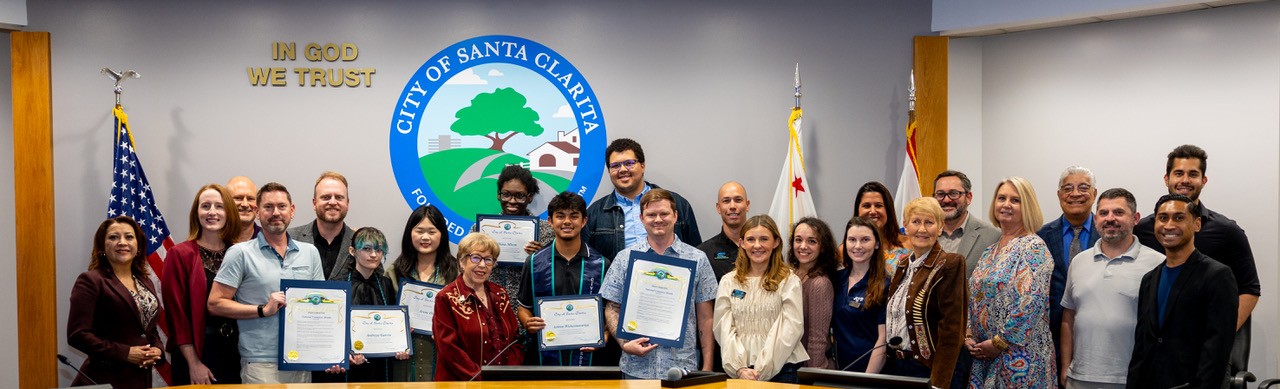 Volunteers taking photo with City Council in front of dais during City Council meeting.