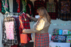 Light Up Main Street attendee looking at clothes in Makers Marketplace booth.
