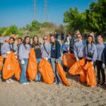 Members of the Saugus Cheer team stand in the Santa Clara riverbed holding orange bags to pick up trash during the annual River Rally.